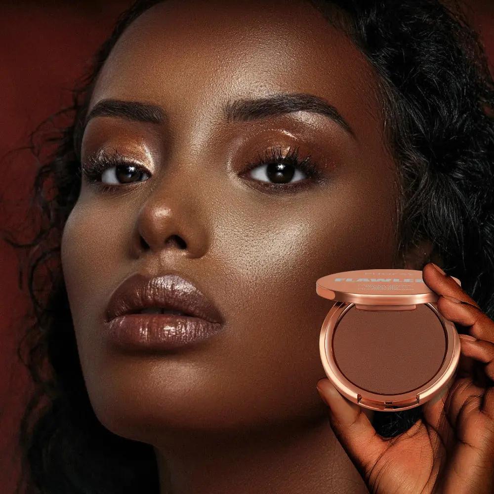 Matte pressed powder compact held near face of woman with deep rich skin tone and smooth matte finish makeup.